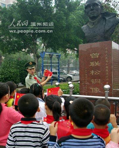 曾联松 瑞安/9月28日，在曾联松铜像前，边防官兵向孩子们讲解国旗的含义。
