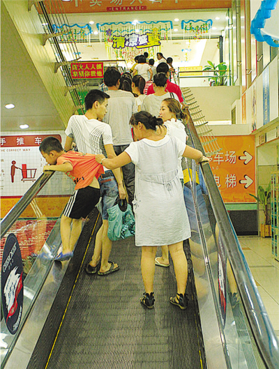在大润发超市,一小孩扒在自动人行道的扶手上