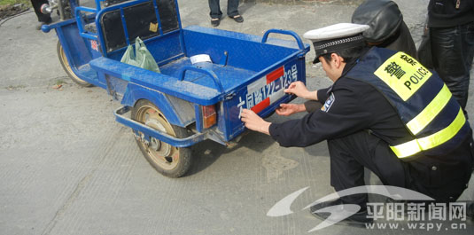 图为县交警大队三中队民警为萧江镇山桥村村民的三轮车贴反光条.