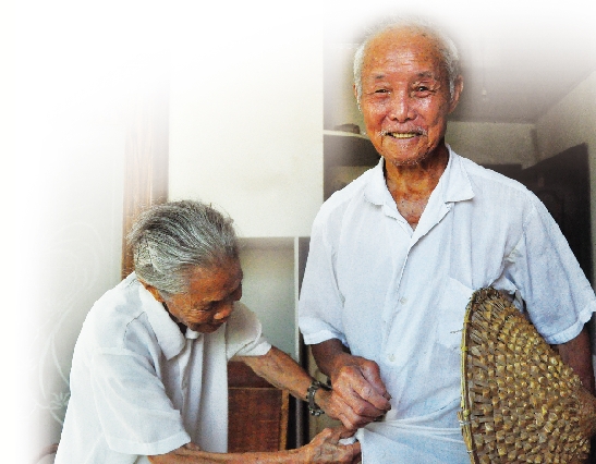 99岁的李正松老人(右)拿起斗笠准备出门,92岁的妻子林来妹老人(左)