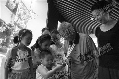 参观展览的小朋友听完抗战老兵周巨瀛的抗战故事后,仔细端详老人的奖章。叶晓东 摄